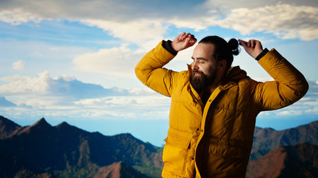 Cheerful hiker celebrates climbing the rugged wilderness with a victory dance, feeling proud of his personal achievement. Nature lover enjoying the lovely mountain landscape.の写真素材