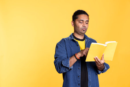 Male book lover feeling happy and pleased reading the book, enjoying a fantasy plot with literature hobby. Young bookaholic guy browsing the novel, book collector.の写真素材