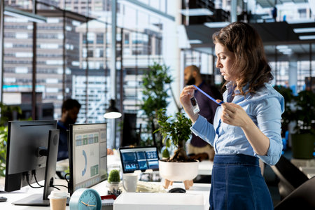 Enthusiastic woman on her first day at new job unpacking things at her workstation, feeling excited and hopeful about joining the team within the corporation. Newcomer unboxing belongings.の写真素材