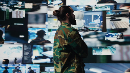 Young soldier working in command center with satellite surveillance integrating data, intelligence and AI warfare tactics for war planning in a national defense mission. Armed forces. Camera B.の写真素材