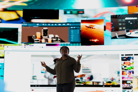 User watching videos highlighting interactive engagement in connected digital environment. African American woman browses online social media feed projected on oversized video wallの写真素材