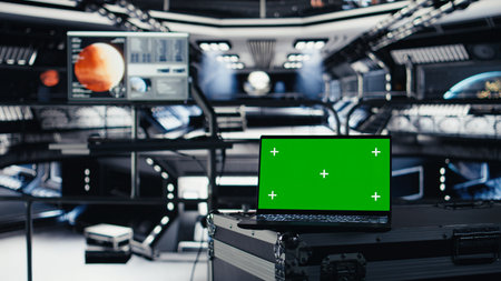 Mockup laptop in orbital station surrounded by high tech displays tracking Mars telemetry. Green screen notebook enabling real time mission control and spacecraft status updatesの写真素材