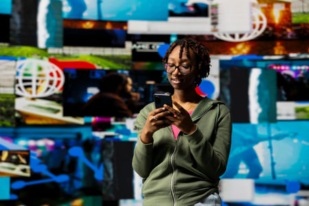 Person watches multimedia collage of modern social media networks videos on smartphone. African american woman using phone looking at visualization of data driven world with content in constant motionの写真素材