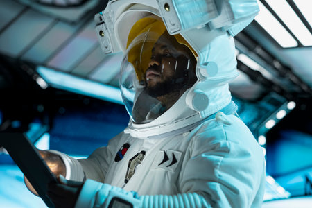 Astronaut using tablet to confirm suit integrity, monitoring life support systems. Orbital station crew member testing gear during routine equipment check using device , conducting safety checksの写真素材