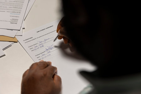 Close up of a man signing work contract with human resources manager, joining the company after reviewing and committing legal paperwork upon agreement. Successful recruitment process for growth.の写真素材