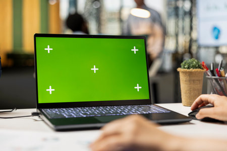 Corporate workspace with close up of laptop showing green screen mockup. Caucasian office worker analyzes financial statistics using isolated chroma key template on digital device.の写真素材