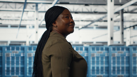 Data center admin conducts security audits to protect against cyber threats and vulnerabilities. Woman walking in server room, ensuring compliance with industry standards, camera Bの写真素材