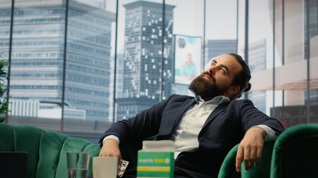 Concerned CEO taking an aspirin to ease the headache due to stress, feeling a discomfort and using painkillers. Tired uncomfortable boss deals with a migraine, burnout and tension. Camera A.の写真素材