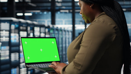 Developer in data center using green screen laptop to upgrade systems for increased stability. IT expert in server farm configuring hardware with mockup notebook for optimum performance, camera Bの写真素材