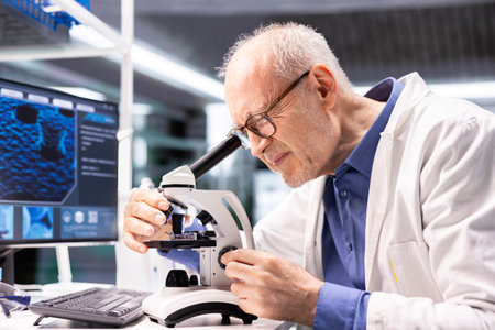 Senior chemist observing specimen under microscope in the laboratory. Clinical experiment illustrates the discovery process in bioscience, pathology and molecular research for innovation.の写真素材