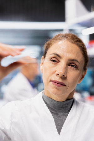 Close up of geneticist examining DNA sample on microscope slide for mutation analysis. Lab expert checking biological specimen preparation before high tech imaging processの写真素材