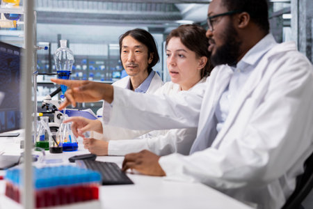 Multiethnic team in laboratory using computer program for DNA data analysis. Diverse research facility coworkers using bioinformatics genomics software on PC in modern labの写真素材