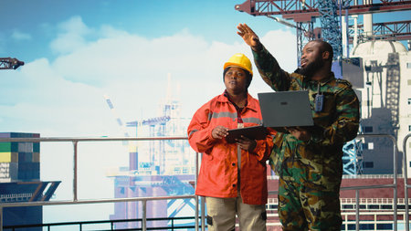 Military personnel stationed on offshore rig analyzing tactical data on laptop. Soldier provides...