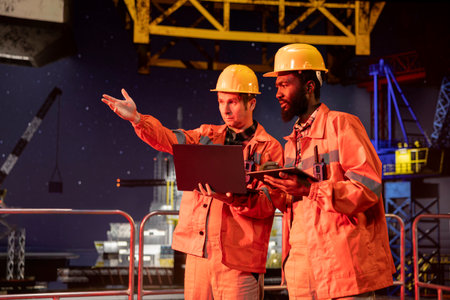 Offshore environmental officers supervises drilling operations on laptop and tablet, focusing on marine ecosystem fossil fuel extraction to promote natural gas resources procurement from oil rig.の写真素材