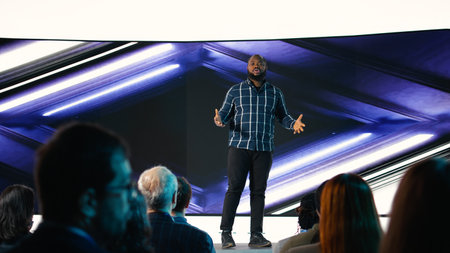 Black product manager introducing new mobile phone product at conference hall, featuring modern...