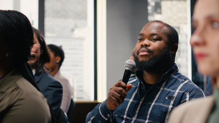 Participants engaging and interacting during presentation, asking questions on microphone. Corporate business meeting with panel discussion and executive speaker, international conference.の写真素材