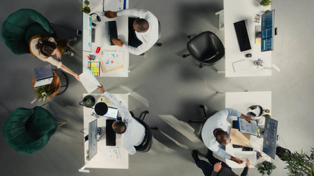 Top down view of business staff in modern office sharing insights and reports, team focuses on data...
