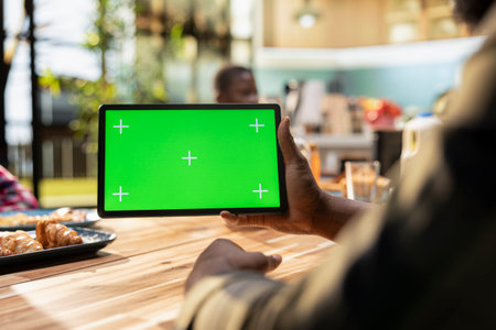 Chroma key next to black family enjoying breakfast at the kitchen table, with plates of omelettes,...