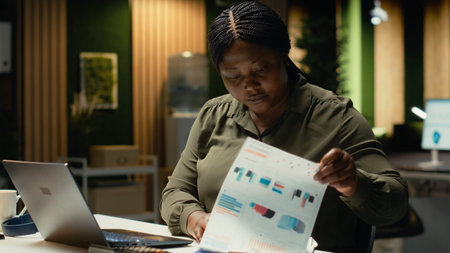 Female employee researching and documenting data reports numbers for data updates and business...