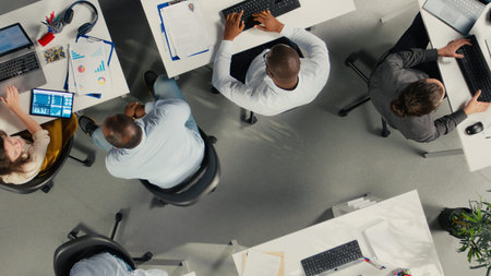 Top down view of business staff in modern office sharing insights and reports, team focuses on data visualization for efficient resource allocation. Company administration.の写真素材