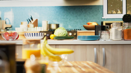 Bright modern kitchen interior with elegant furniture and wooden cupboards. Cookware and fresh vegetables on a cutting board, showcasing a stylish household and luxury home design.の写真素材