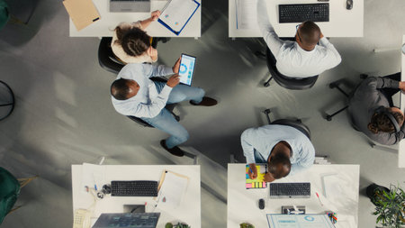 Top down view of corporate workers assessing business objectives and targets. Charts, diagrams and...