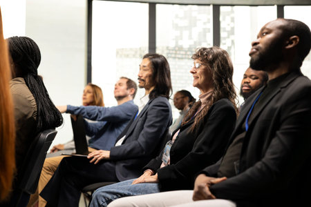 International business event with professional diverse attendees seated on chairs. Audience listening to presentation during panel discussion, encouraging engagement and discussion among attendees.の写真素材