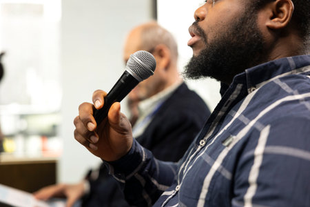 African american participant engaging and interacting during presentation, asking questions on microphone. Corporate business meeting with panel discussion and speaker, international conference.の写真素材
