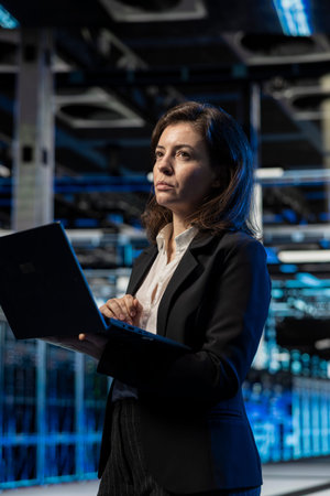 Data center female engineer using laptop, managing server virtualization. Computer scientist using...