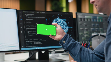 Green screen smartphone used by engineer in Silicon Valley company office developing apps. IT expert creating videogames on chroma key phone, debugging issues, close upの写真素材