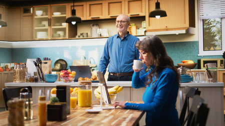 Aged man in the kitchen shows joyful lifestyle during retirement. Elder person serving coffee cup in...