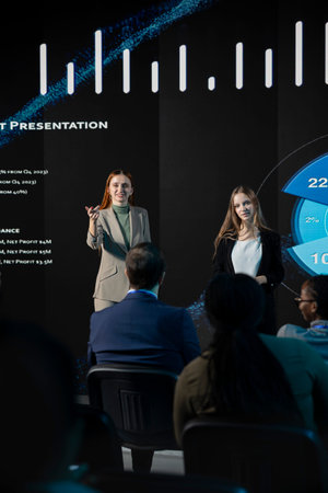 Two female speakers taking the stage for a business presentation at the international conference event, discussing entrepreneurship tactics. Development convention in auditorium.の写真素材