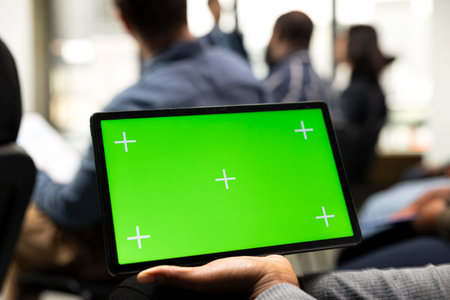 Mockup display on tablet at business convention event with guest speaker and panel discussion. Diverse audience of professionals listening to presentation focused on leadership.の写真素材