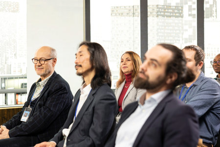 Diverse people in audience listening to guest speaker during business forum with panel discussion,...