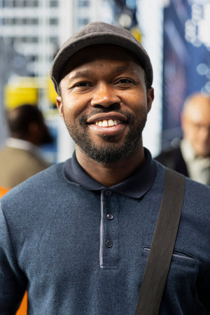 Portrait of a black adult male in casual clothes on a downtown street, urban crowd of multicultural...