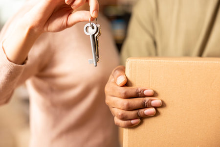 Close up of caucasian girlfriend holding keys and african american boyfriend with moving box, symbolizing fresh start in shared home. Multiethnic couple representing relocation and new beginnings.の写真素材
