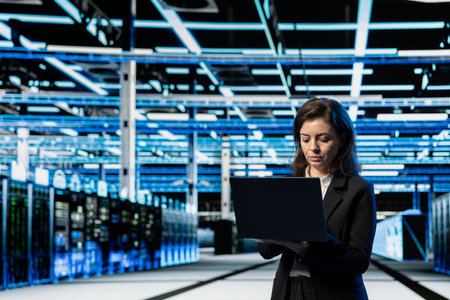 Data center engineer using laptop to do maintenance on cloud computing gear, VFX compositing...