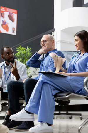 Healthcare professionals discuss test results, treatment steps and recovery during medical appointment. Senior patient appears nervous and anxious while anticipating diagnostic results in clinic.の写真素材