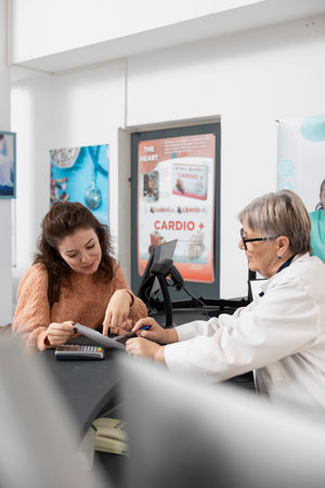 Adult female customer clarifying prescription instructions with senior pharmacist at drugstore...