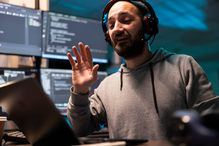Caucasian IT specialist wearing headset speaks during virtual meeting at desk. Multiple digital...