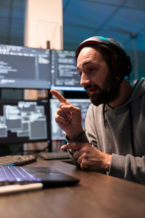 Male programmer participates in video call while working at multimonitor coding setup. Developer...
