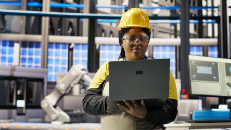 Engineer performing predictive maintenance using laptop, analyzing IoT sensor data, managing operational reliability of photovoltaic systems in smart factory environment, camera Bの写真素材