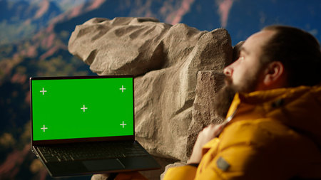 Nature lover stands on a mountain top next to copy space display, looking out at the scenic...