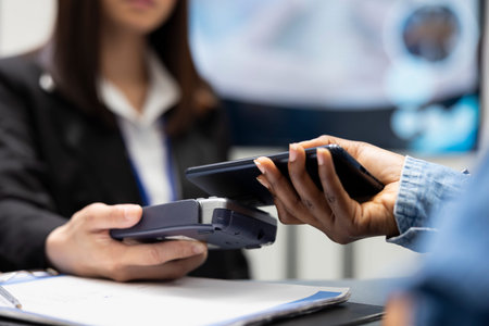 Patient using smartphone for cashless medical payment as clinic receptionist processes transaction...