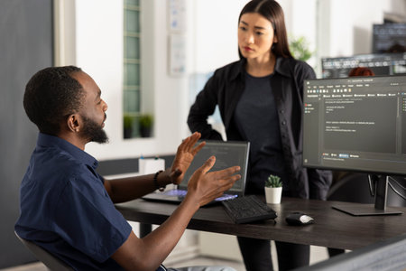 Manager reviews application progress as coworker presents updated software code information. The...