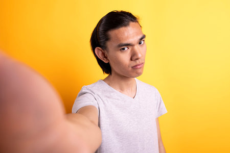 Pov of asian man taking selfie with sad expression. Frustrated content creator holds camera,...