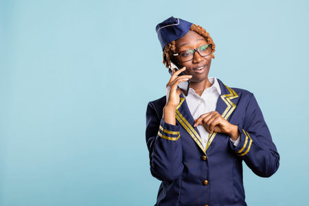 Flight attendant speaks with colleagues on cellphone, showing surprised facial reaction after...