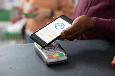Person completing pharmacy checkout by tapping mobile phone on pos terminal. Contactless transaction...