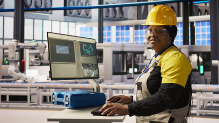 Portrait of cheerful factory engineer typing on PC, overseeing monitoring of production lines. Jolly...