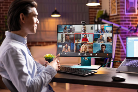 Focused businessman attending online meeting, looking at computer screen and listening to remote...